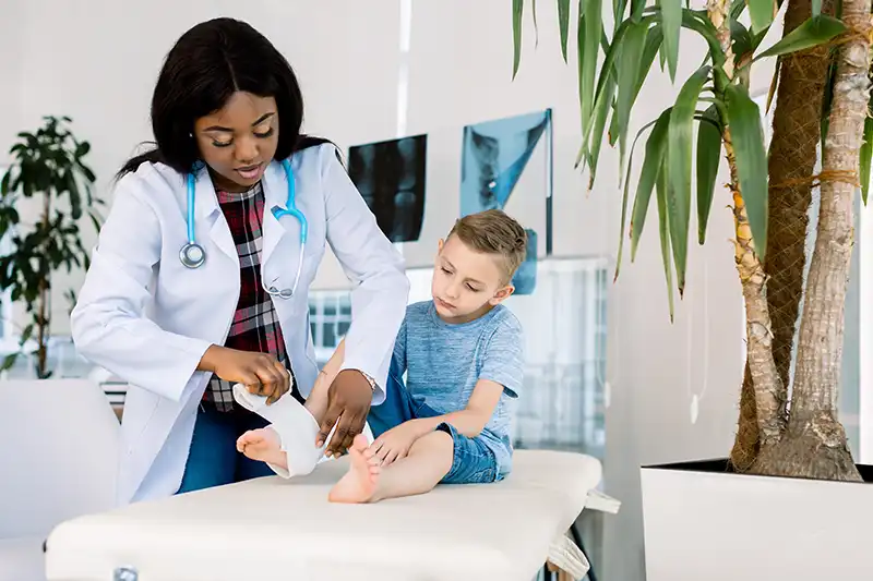 A boy getting his foot wrapped by the doctor