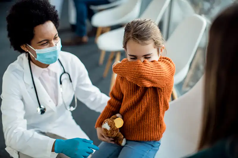 A young girl coughing while seeing the doctor