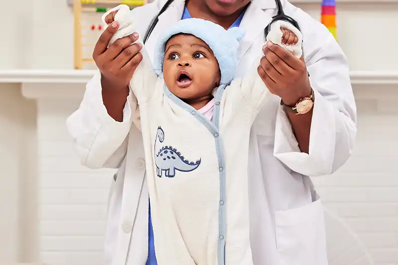 Baby being held up by the doctor while trying to stand