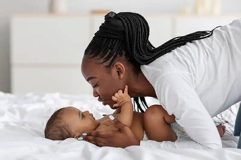 black-mom-playing-in-bed-with-her-infant