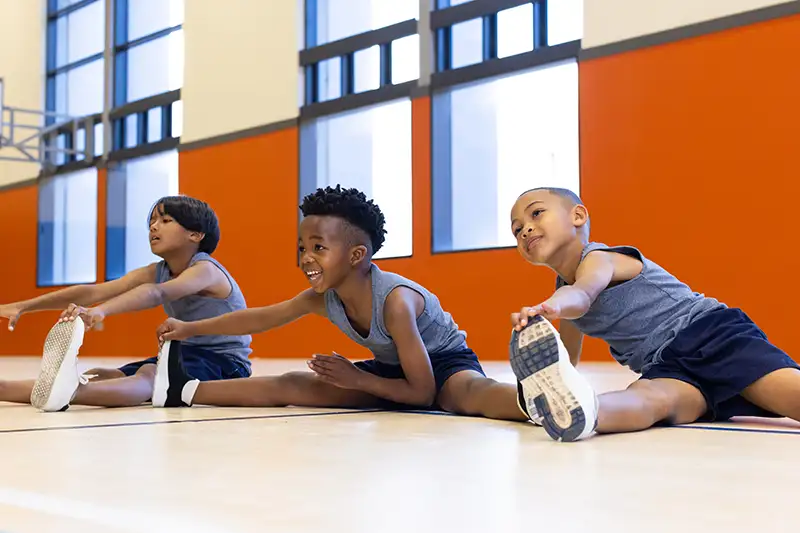 in school gym three multiracial boys stretching